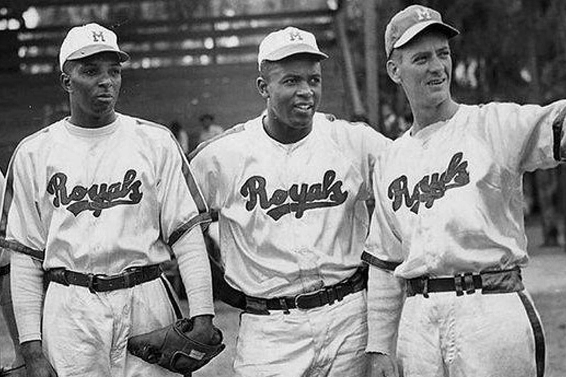 Black-and-white photo of three baseball players in Royals uniforms standing together on the field.